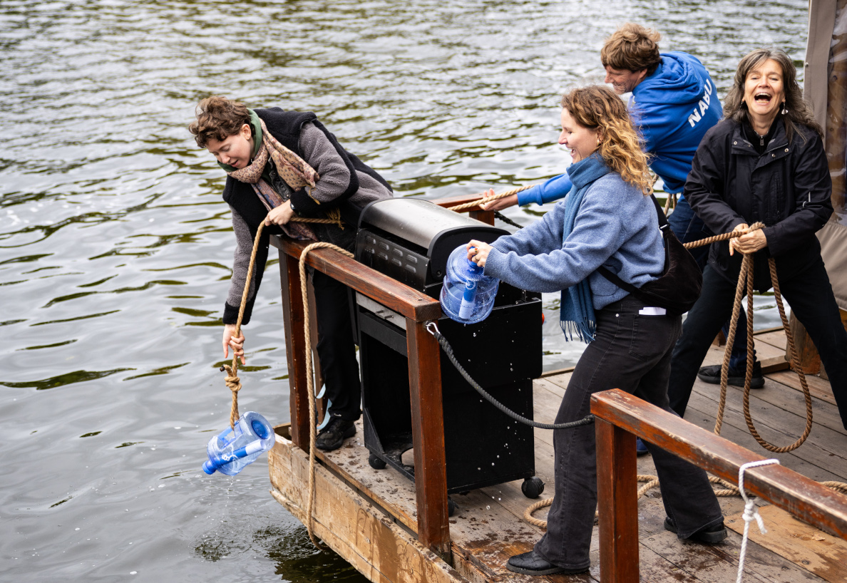 Aktivist*innen ziehen Forderungen der Wasservernetzung Brandenburg-Berlin aus einer Flaschenpost aus der Havel
